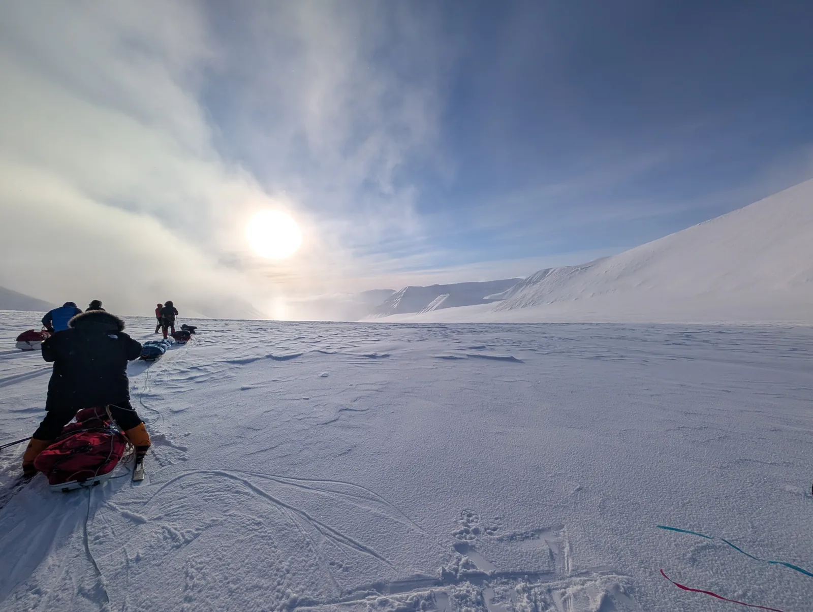 Two of the group hauling pulks toward the low sun, Svalbard